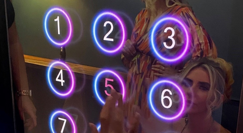 A guest entering their phone number on the illuminated keypad of a magic mirror photo booth